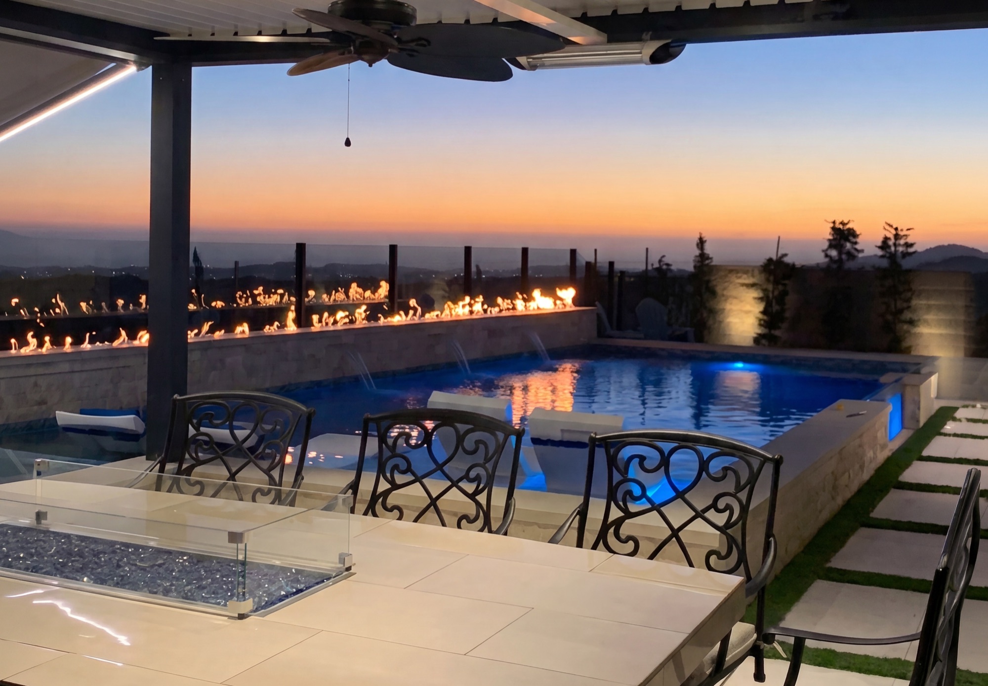 Sunset view from covered patio across pool with fire features in Baker Ranch, CA
