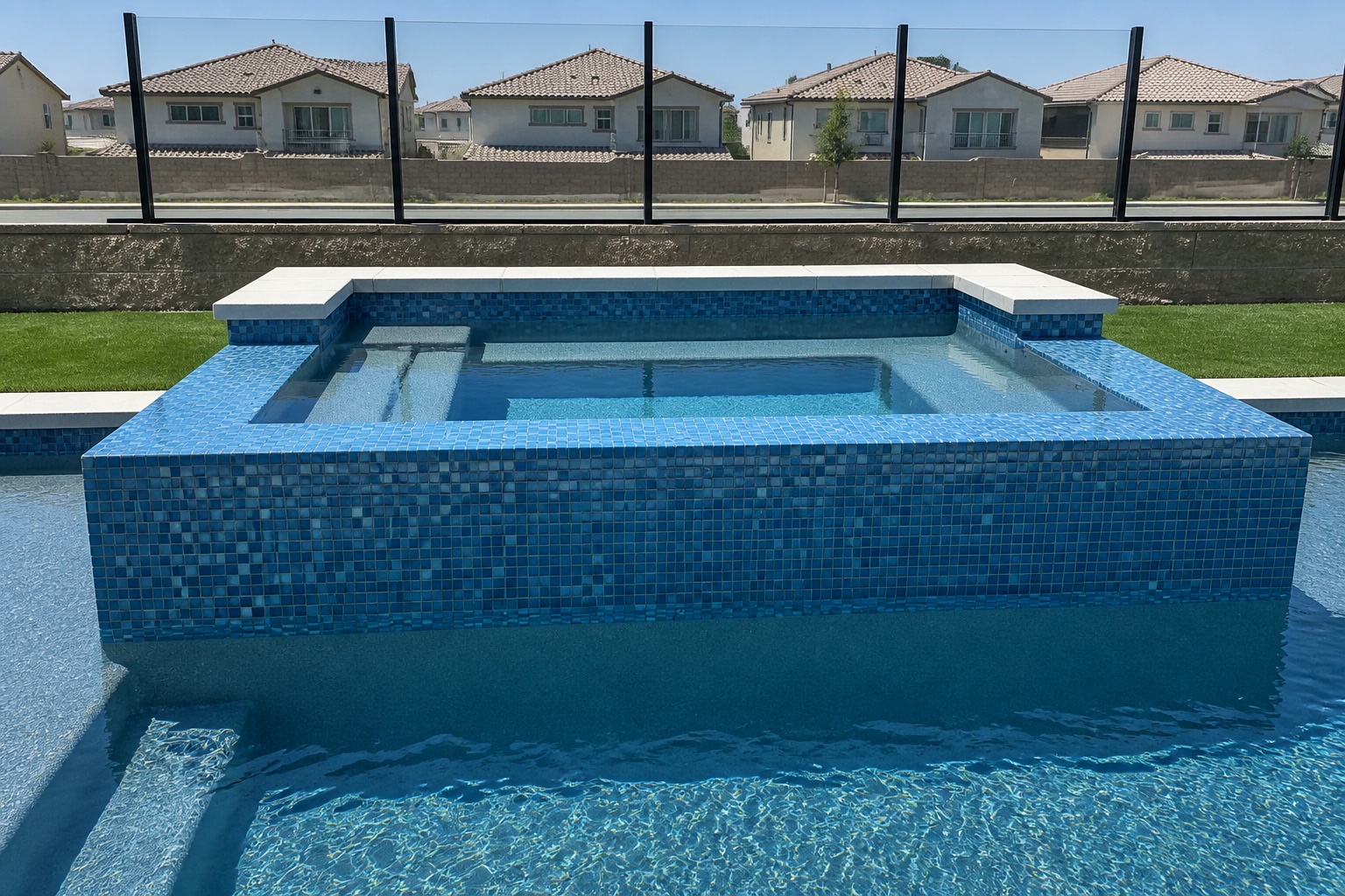 Front view of raised spa in blue glass mosaic tile spilling into the pool in Portola Hills, CA