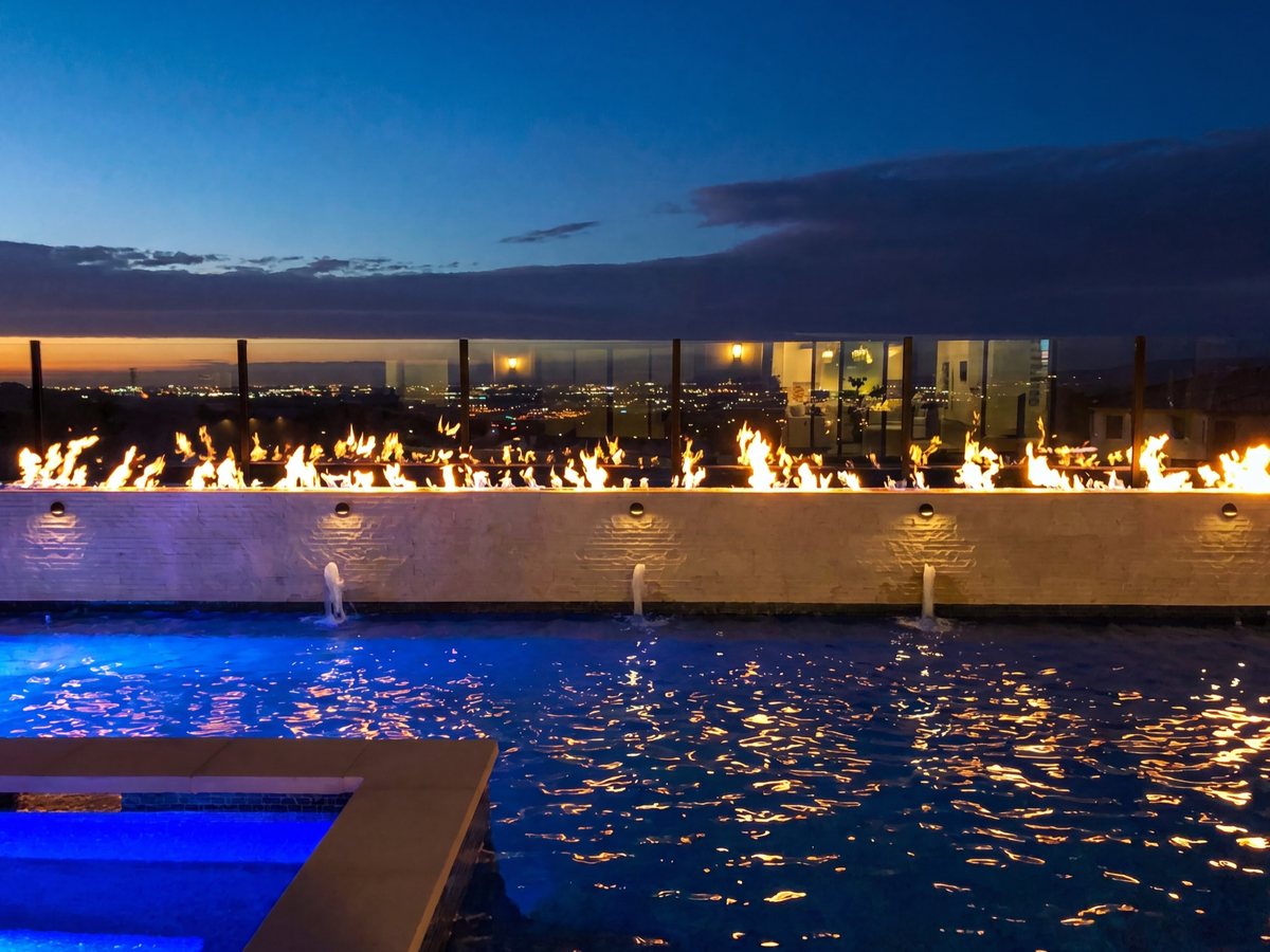 Pool fountains and linear fire feature glowing at dusk