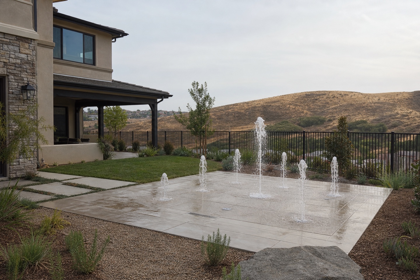 Backyard splash pad with fountain jets, turf, and hillside views in Rancho Mission Viejo